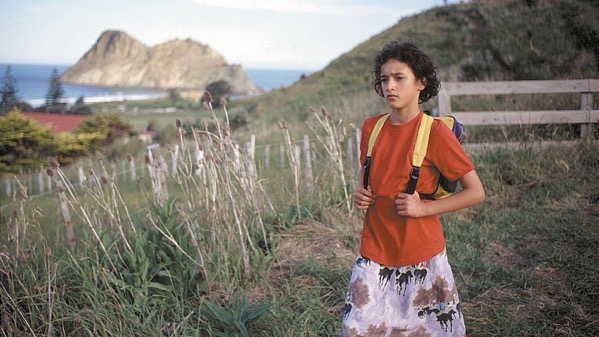 photo of young girl wearing backpack, with view to ocean in the backgroun; still from "Whale Rider"